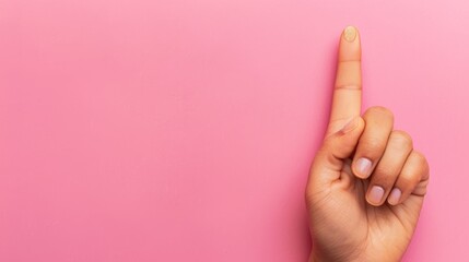  A woman points to her left, finger touching a pink surface against a pink backdrop