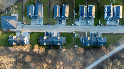 Top-down view of new residential houses among trees, solar panels on the roof.