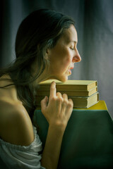 woman in a white blouse with a Carmen neckline with her hands resting on an old book in a romantic attitude III
