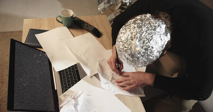 Symbolic Secrets: Man in Tin Foil Hat Sketching Esoteric Signs