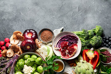 Vegan food. Pepper, broccoli, cabbage, garlic, mushrooms, pomegranate on a dark background