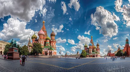 Gordijnen A panoramic view of the Moscow Red Square, showcasing St Basil's Cathedral and Sretenskymoskull tower, bathed in sunlight with blue sky above © Kien