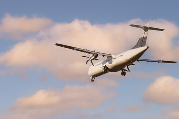 Rear view of an ATR 72 airplane among the clouds at sunset. Twin-engine turboprop short-haul...