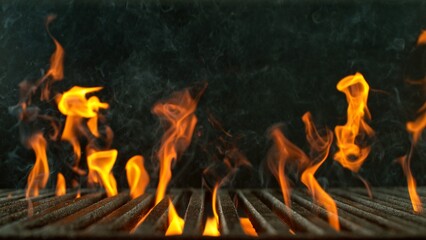 Close-up of cast-iron grate with fire flames, dark background - 768737594