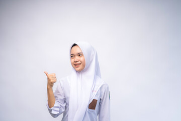 portrait of Indonesian high school student in white and grey uniform giving thumbs up at Copy Space Advertising Your Text. Education concept