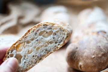 A slice of fresh wheat baguette with seeds. Selective focus. Bread with poppy seeds