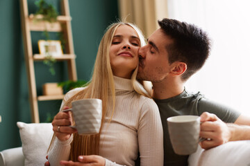Beautiful young happy couple enjoying coffee at home on sofa - 768743133