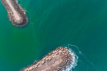 Obraz premium aerial top view of the breakwaters at the entrance of a harbor