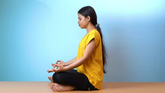 Beautiful woman practicing Siddhasana, also known as Accomplished pose or Perfect pose yoga, isolated indoor home background
