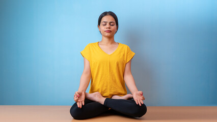 Beautiful woman practicing Padmasana, also known as Lotus pose yoga, isolated indoor home background
