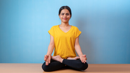 Beautiful woman practicing Padmasana, also known as Lotus pose yoga, isolated indoor home background