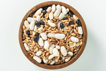 mix of barley and black and white beans in a wooden bowl on a white background. soup set