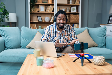 Young African exchange student expatriate freelance business man sitting at home talking on video call on webcam with his family back home. African American online seller working from home.