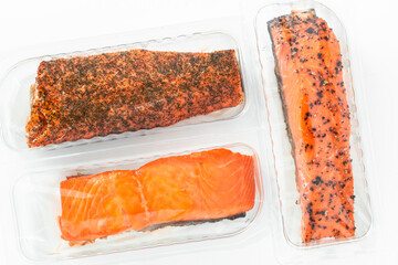 a piece of smoked salmon with black pepper and dried herbs in a package on a white background