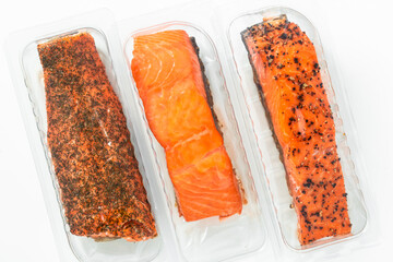 a piece of smoked salmon with black pepper and dried herbs in a package on a white background