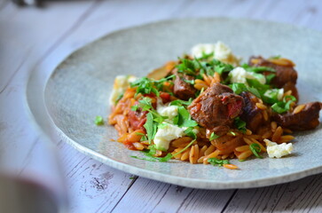 Rice with lamb meat and vegetables on a plate on a wooden table