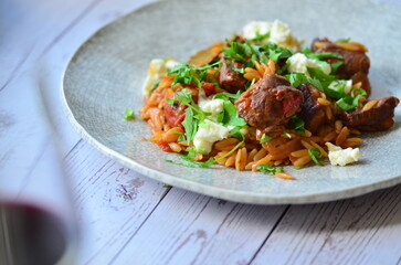 Rice with lamb meat and vegetables on a plate on a wooden table