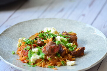 lamb stewed with tomatoes and orzo, background of greek traditional food youvetsi