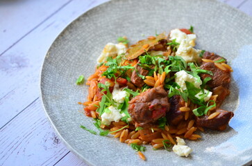 Rice with lamb meat and vegetables on a plate on a wooden table