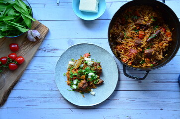 Rice with lamb meat and vegetables on a plate on a wooden table