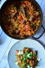 rice with meat and vegetables in a frying pan on a wooden background