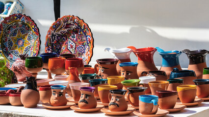 Earthenware pots with whimsical faces, paired with vibrant decorative plates. Traditional Turkish...