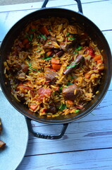 rice with meat and vegetables in a frying pan on a wooden background