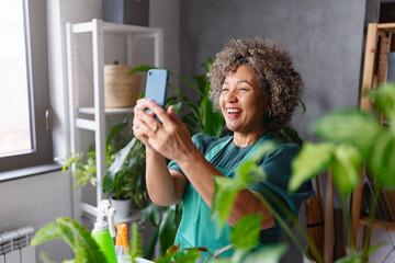 Mature smiling woman gardener taking a selfie photo in her home garden - 768777340