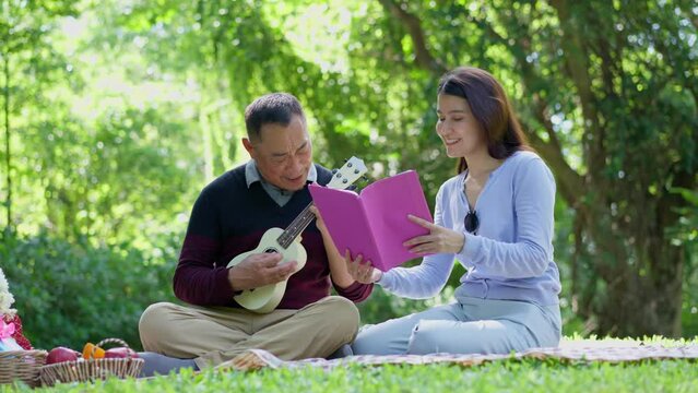 Daughter comes to visit parents and picnic in park, family, leisure and people concept - happy fathers, elderly caregiver, enjoying outdoor on picnic blanket reading book in park at sunny time