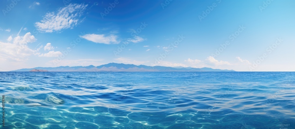 Poster A serene view of the ocean with exceptionally clear water and majestic mountains in the far distance