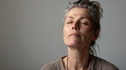 Woman with closed eyes deep in thought or meditation against a neutral background.