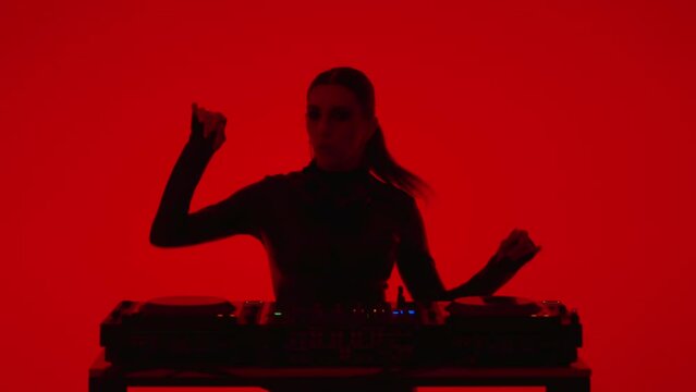 Joyful Young Woman DJ Dancing And Mixing Tracks In Studio With Red Background, Medium Portrait