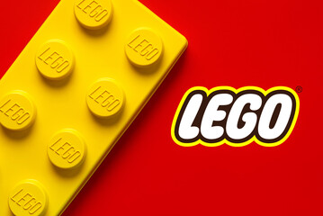 Naklejka premium Close up of large yellow lego block with the Lego logo. Illustrative editorial