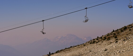 Portrait shot of a pink sunset featuring two ski lifts gliding up and down