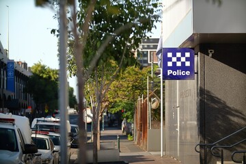 Sunny street scene with a police station sign visible in the foreground