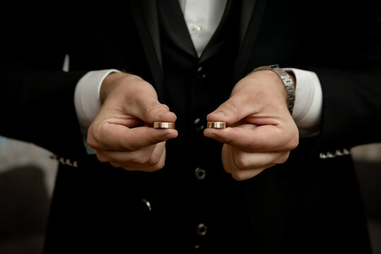 The groom holding the wedding rings in his hand	