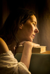 woman in a white blouse with a Carmen neckline with her hands resting on an old book in a romantic attitude IV