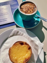a cup of coffee, a small Portuguese egg-filled cookie, sweets, a sea cup