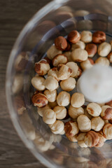 This high-resolution image captures a close-up view of a bowl filled with hazelnuts. The bowl is placed on a wooden surface, adding to the organic and rustic aesthetic of the photograph. 