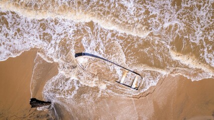 Sunken small fishing boat buried in the sand