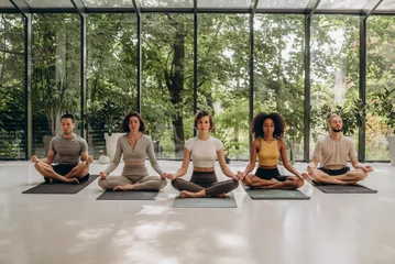 Foto op Plexiglas Group of people sitting in lotus pose on yoga mats in studio © sashafolly
