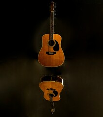 Acoustic guitar on a dark background, reflecting on the ground