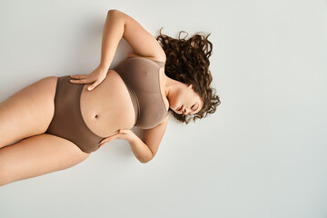 plus size young girl in brown underwear with hands on waist and closed eyes leaning head - 768800568