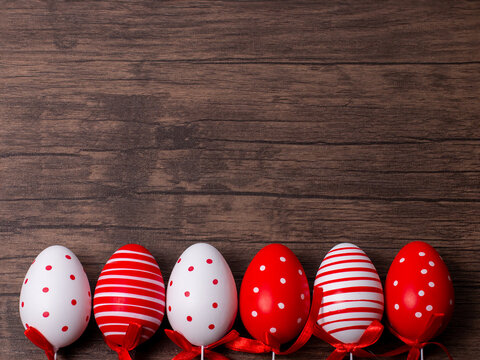 Red and white easter eggs on the bottom side of a wooden table. Graphic resource with space for text.