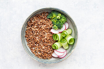 buckwheat porridge with cucumbers, radishes and broccoli in a bowl. gluten free food