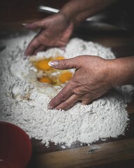 Woman kneading eggs in flour for making dough