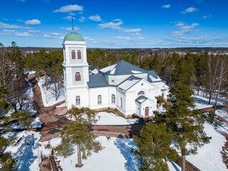 a white church with trees and snow on the ground in front