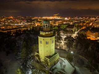 High-rise building illuminated by lights standing atop a hillside blanketed in snow: Kotka, Finland