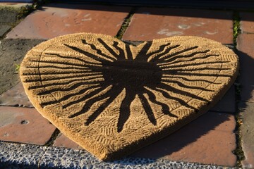 heartshaped doormat with a sunburst pattern and someones shadow over it