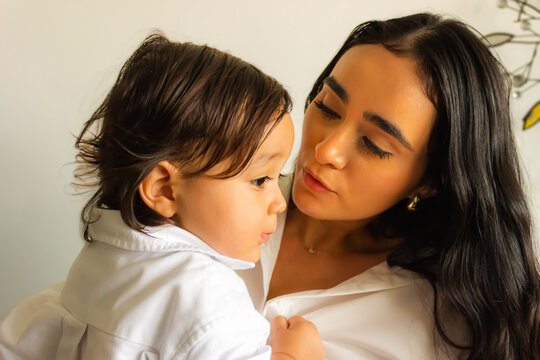 Latina mother speaks lovingly to her baby son while holding him in her arms